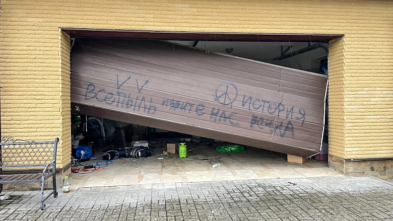 Russian graffiti on Yakovlyev's garage door translates to, "History all is dust. Forgive us war."