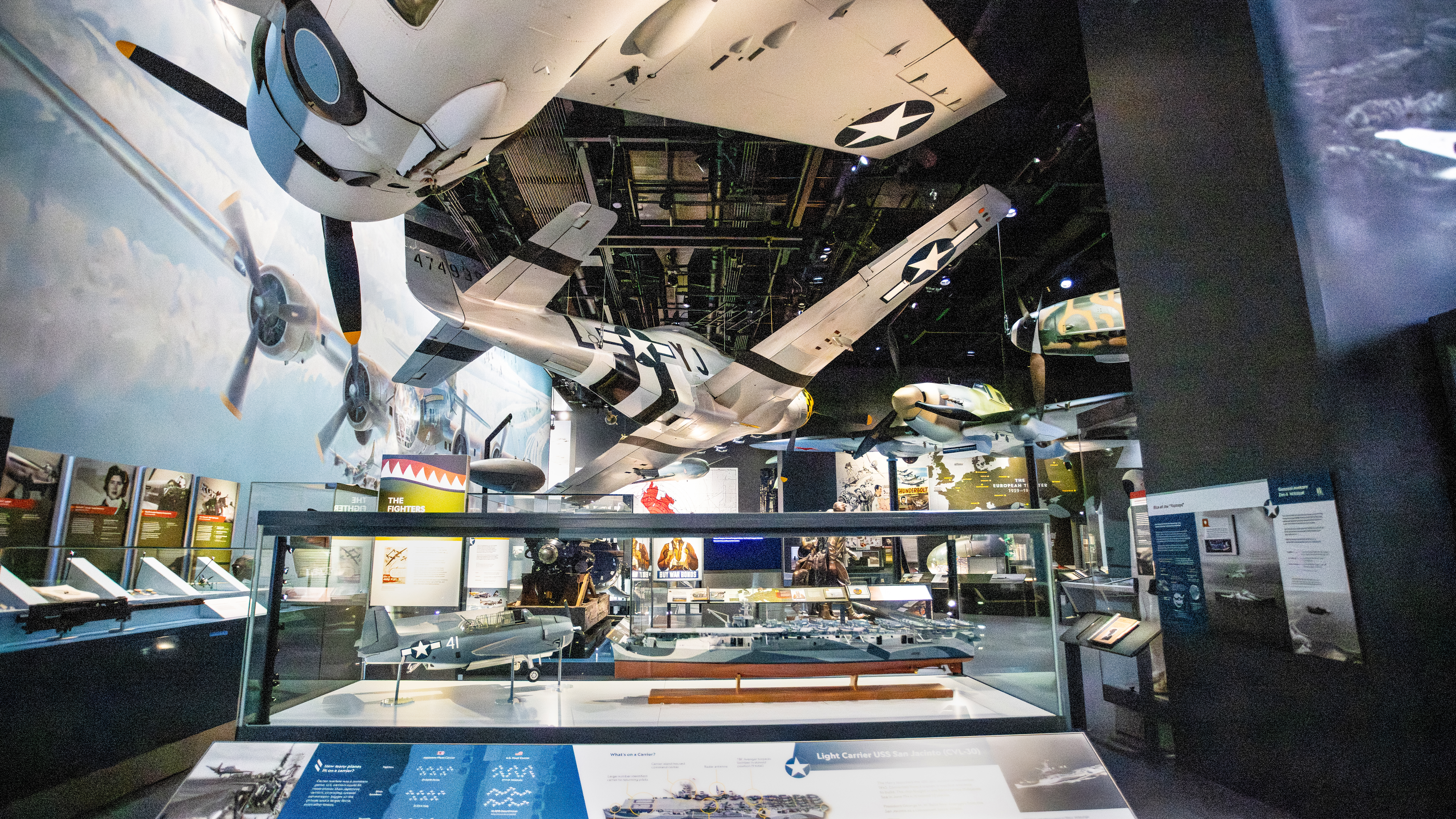 Aircraft such as the North American P–51D Mustang, Messerschmitt Bf 109, and Ilyushin IL–2 “fly” overhead in the gallery.