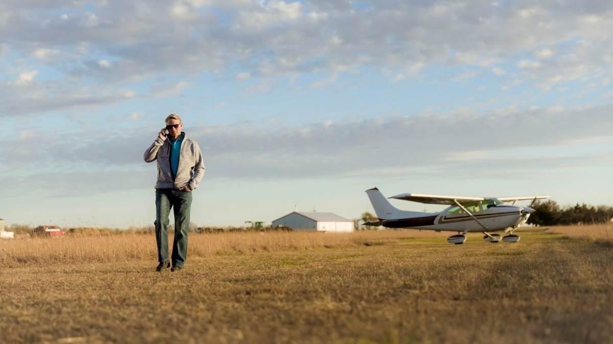 pilot retreating from his recently parked aircraft on an old wheat field