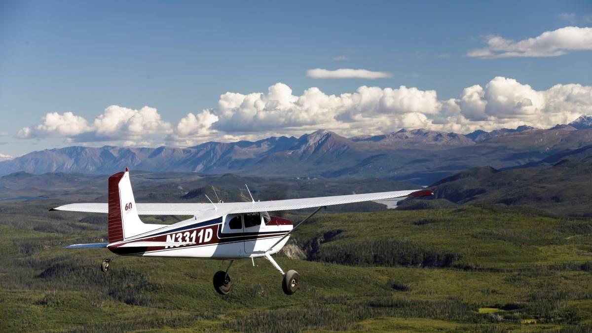 white cessna flying low toward an mountainous horizon