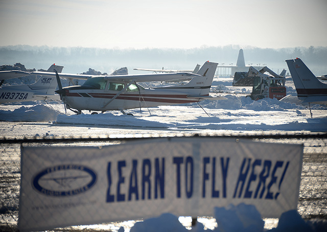 Snow removal equipment is deployed around parked Cessna aircraft during cleanup operations after a mid-Atlantic blizzard brought more than two feet of snow, high winds, and whiteout conditions to AOPA headquarters at Frederick Municipal Airport in Frederick, Maryland. Photo by David Tulis.