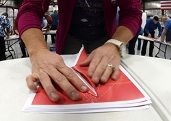 A participant carefully folds a paper airplane along dotted lines to speed construciton during the world record attempt March 8. Photo by David Tulis.