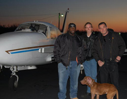G, far left, and Joe, far right, stand with a volunteer pilot and the pit bull they brought from Kentucky to Long Island. The pit bull had serious injuries and was likely used as a "bait dog" to train fighting dogs. 