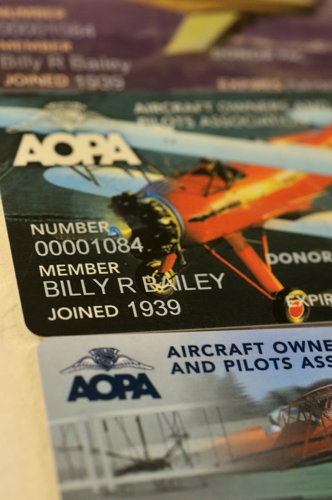 Bill Bailey displays some of his many AOPA membership cards on the wall of his condo.