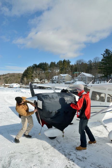 Pilots cover the engine of their aircraft during a visit to Alton Bay.