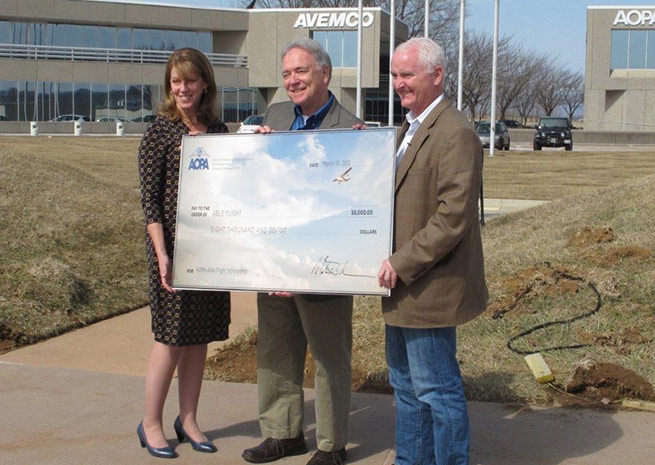 AOPA President Mark Baker (right) and AOPA Foundation Vice President of Strategic Philanthropy Stephanie Kenyon (left) present Able Flight Executive Director Charles Stites with an $8,000 check.