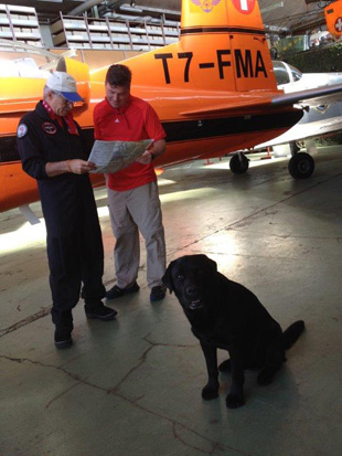 AOPA member Russ Sanders prepares for a flight in a Pilatus PC-7 while the lovable hangar dog looks on.