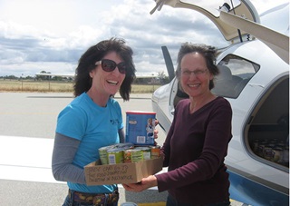 SCAPA pilot and longtime board member Bette Gardner hands the first food donation to Vicky Martin of the St Joseph’s Family Center Food Pantry program. Photo courtesy of SCAPA/Paul Marshall.