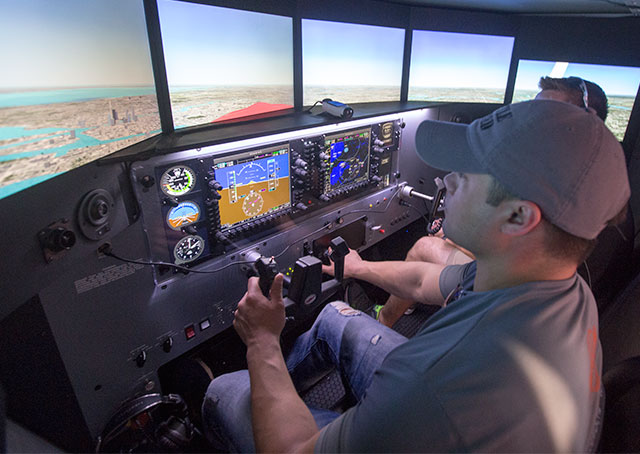 Nik Oekerman (left) gets some instruction from Jeff Wolf in a Redbird simulator April 20. 