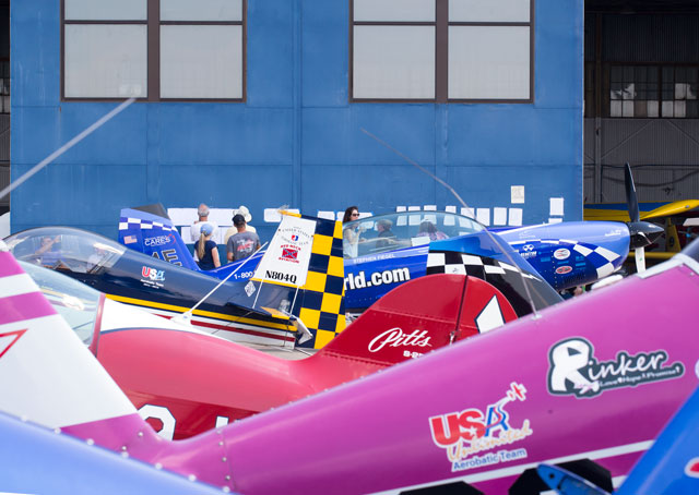 Competitors’ aircraft lined up in front of the blue hangar door where contest scores and pilot lineups are posted daily during the national championships. Jim Moore photo. 