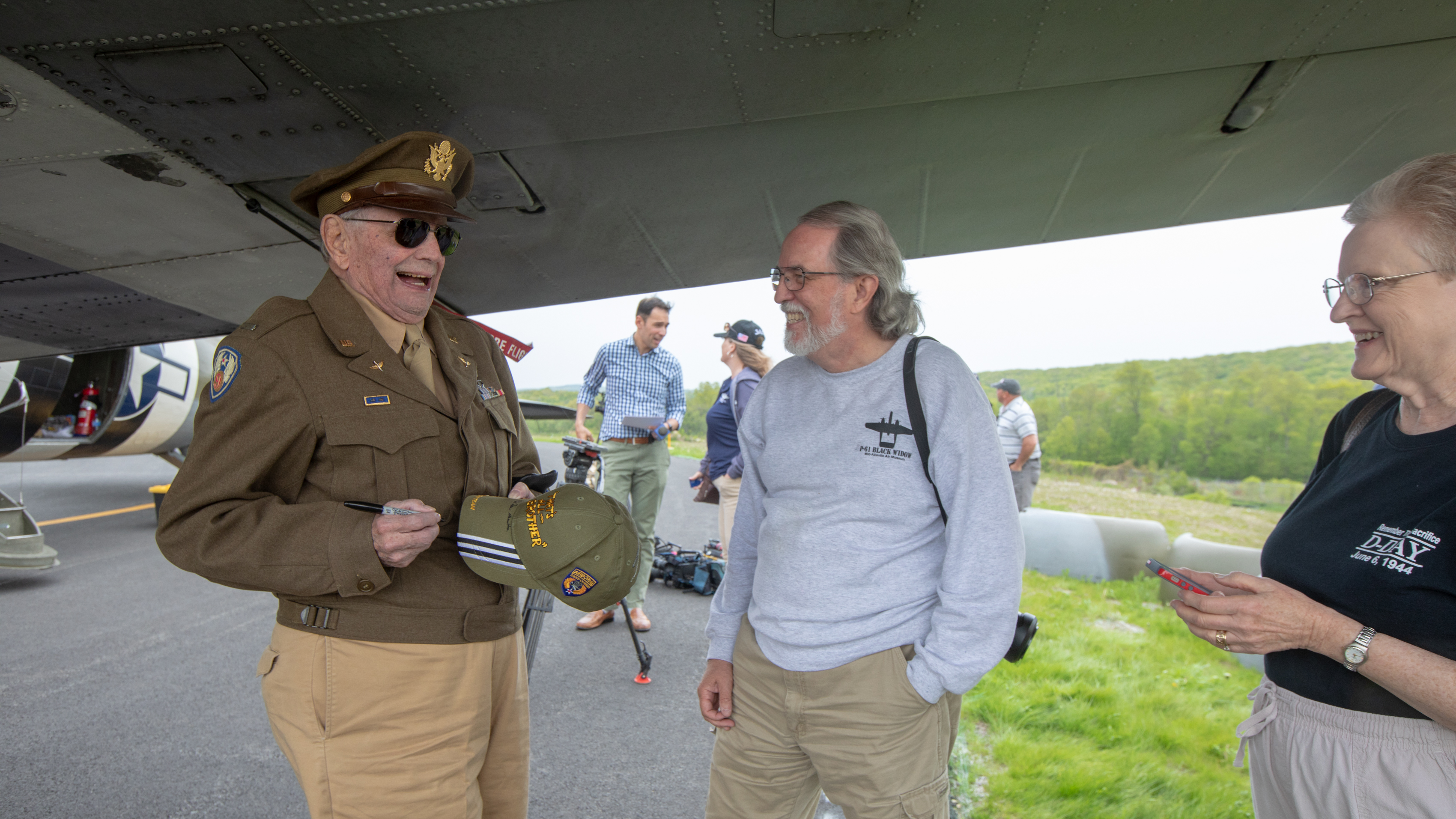 Retired Lt. Col. Dave Hamilton autographs a commemorative cap for Alabama residents Mike and Lorane Brown, who made the trip to Waterbury-Oxford Airport in Connecticut to see the D-Day Squadron. Photo by Jim Moore.